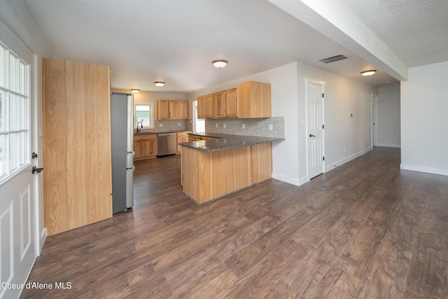 kitchen with stainless steel appliances, a peninsula, visible vents, and dark wood-style flooring