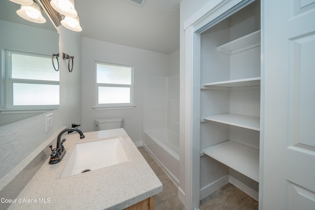 full bathroom with toilet, vanity, and an inviting chandelier