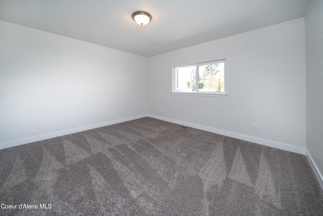 spare room with dark carpet and baseboards