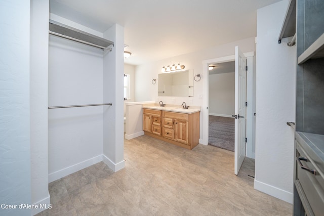 bathroom featuring baseboards, a sink, and double vanity