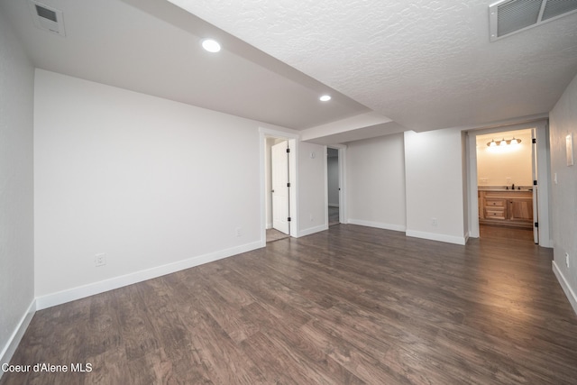 finished basement featuring dark wood-style floors, baseboards, visible vents, and recessed lighting