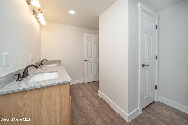 bathroom with wood finished floors, baseboards, and a sink