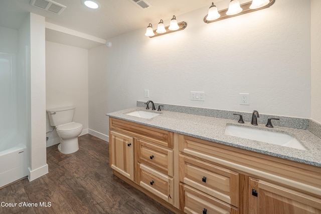 bathroom with wood finished floors, visible vents, toilet, and a sink