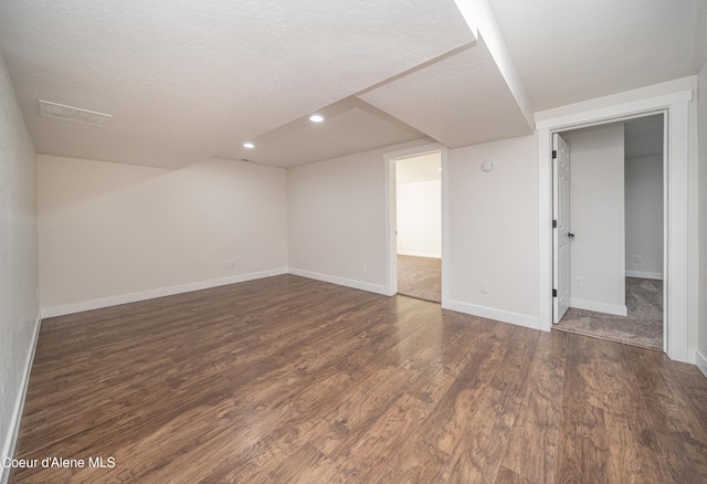 finished below grade area with recessed lighting, a textured ceiling, baseboards, and dark wood-style flooring