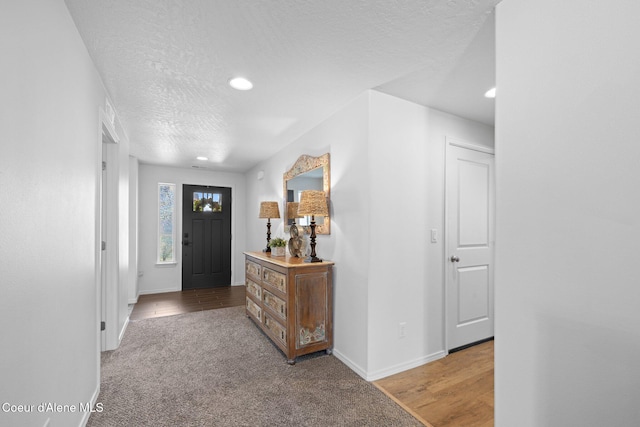 carpeted foyer entrance featuring recessed lighting, a textured ceiling, and baseboards