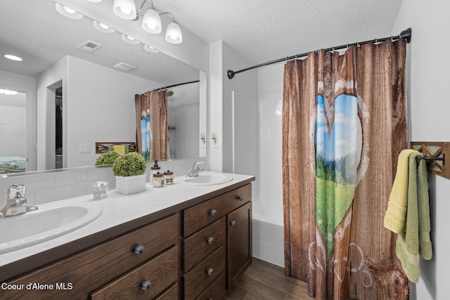 bathroom featuring visible vents, a sink, wood finished floors, and shower / tub combo with curtain