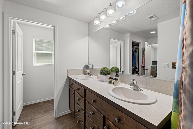 bathroom featuring visible vents, a sink, a textured ceiling, and wood finished floors