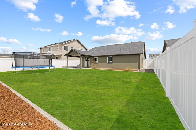 rear view of house with a fenced backyard, a trampoline, a lawn, and a patio