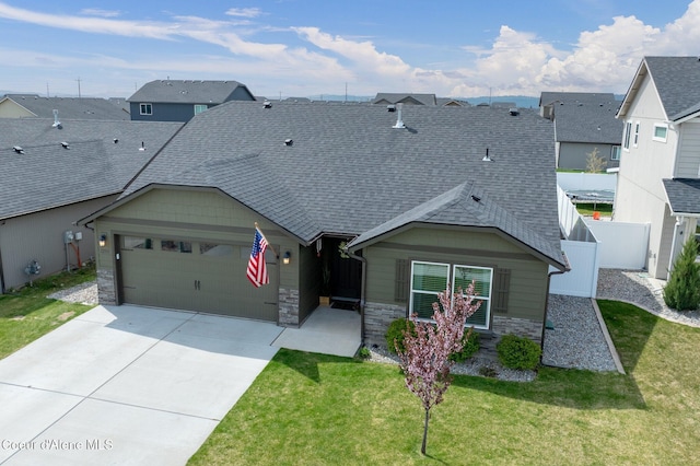 ranch-style home featuring fence, an attached garage, roof with shingles, and stone siding