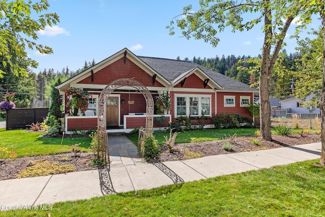 view of front of property with a porch, fence, and a front yard