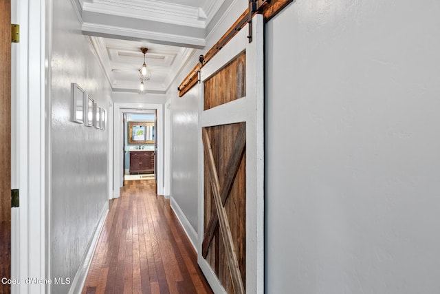 hall featuring crown molding, a barn door, baseboards, and hardwood / wood-style flooring