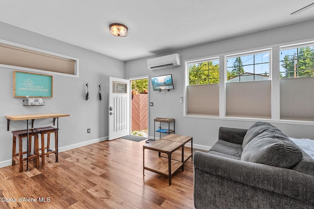 living room featuring baseboards, plenty of natural light, a wall mounted AC, and wood finished floors