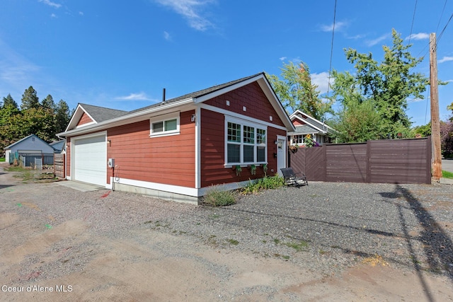 view of property exterior featuring a garage, fence, and driveway