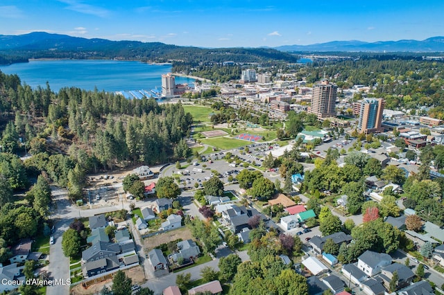 aerial view featuring a water and mountain view and a view of trees