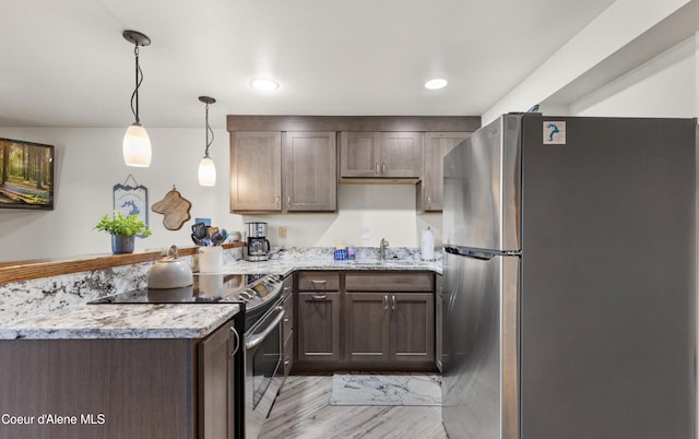 720 N 3rd Ave Unit 12, Sandpoint, ID 83864 - kitchen featuring stainless steel appliances, a peninsula, a sink, light wood finished floors, and light stone counters