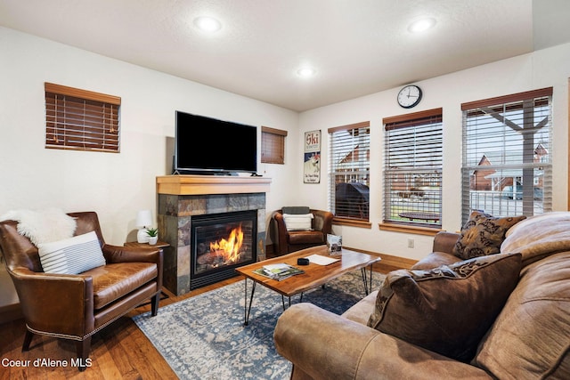 living area featuring recessed lighting, a tiled fireplace, wood finished floors, and baseboards
