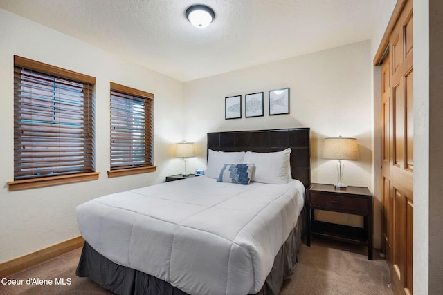 carpeted bedroom featuring a textured ceiling and baseboards