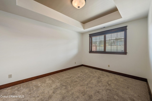 carpeted empty room with baseboards, visible vents, and a raised ceiling