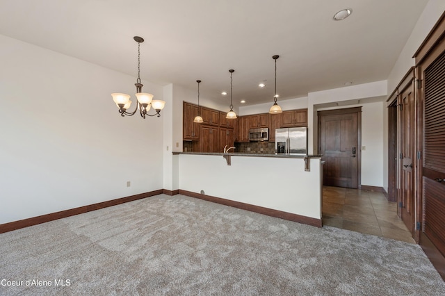 kitchen featuring dark countertops, stainless steel appliances, baseboards, a peninsula, and tasteful backsplash
