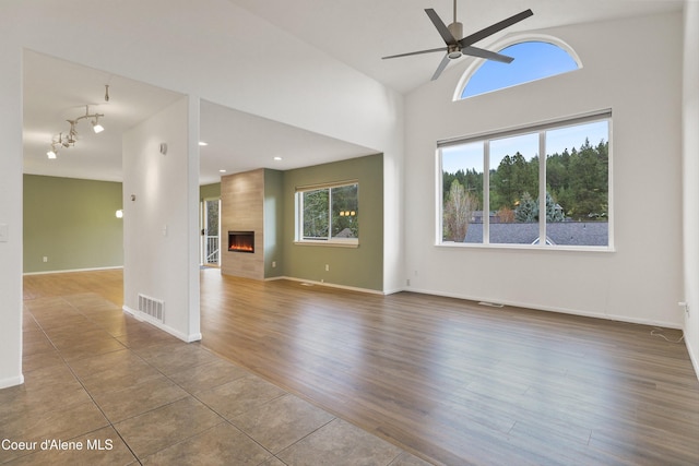 956 N Armstrong Dr, Coeur Dalene, ID 83814 - unfurnished living room featuring ceiling fan, tile patterned flooring, a large fireplace, baseboards, and lofted ceiling