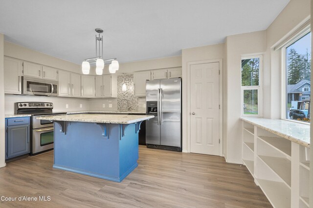 956 N Armstrong Dr, Coeur Dalene, ID 83814 - kitchen with appliances with stainless steel finishes, a kitchen breakfast bar, light wood-style floors, and light stone counters