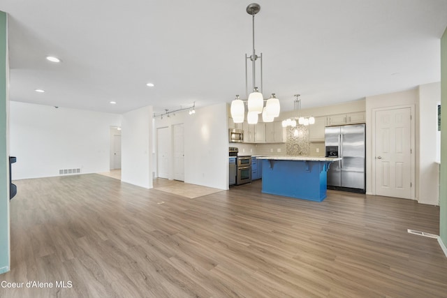 956 N Armstrong Dr, Coeur Dalene, ID 83814 - kitchen with stainless steel appliances, open floor plan, a breakfast bar, light wood-type flooring, and light countertops