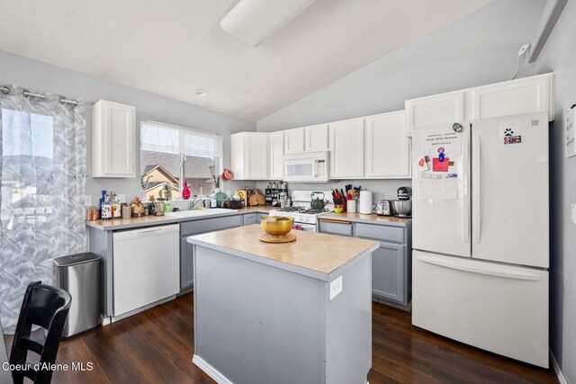 kitchen featuring a sink, white appliances, light countertops, dark wood finished floors, and vaulted ceiling