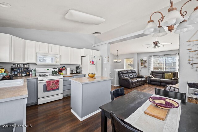 kitchen with dark wood-style flooring, a sink, white appliances, light countertops, and vaulted ceiling