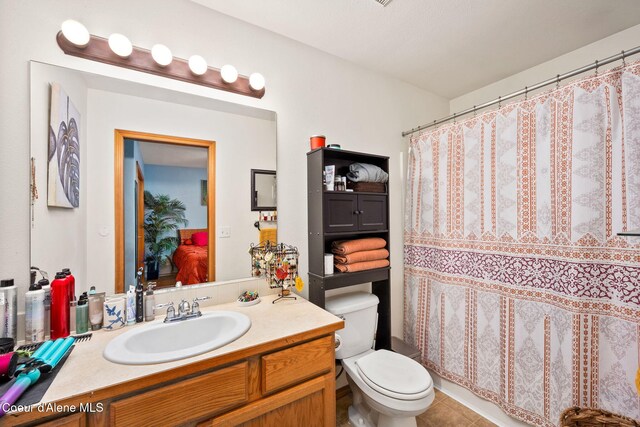 bathroom featuring vanity, tile patterned flooring, toilet, and curtained shower