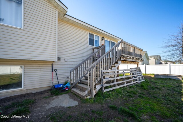 rear view of property with stairs, a wooden deck, and fence
