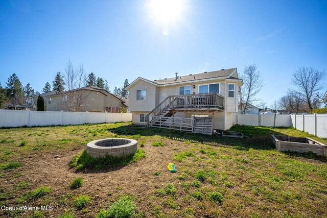 rear view of house featuring a deck, a vegetable garden, a fenced backyard, a fire pit, and stairs
