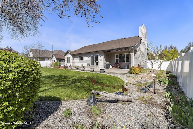 rear view of house featuring a patio, a fenced backyard, a yard, and a chimney