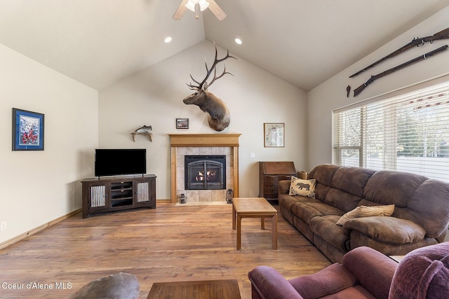 living area with high vaulted ceiling, a tiled fireplace, a ceiling fan, recessed lighting, and wood finished floors