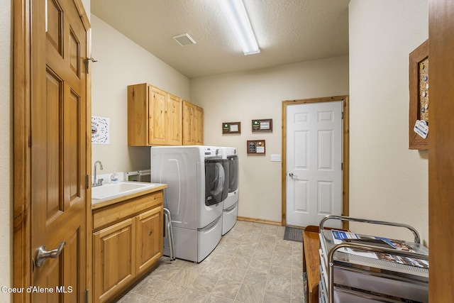 washroom featuring a sink, visible vents, cabinet space, and washer and dryer