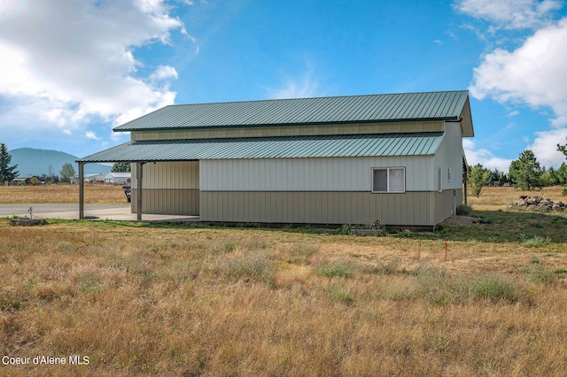 view of property exterior featuring an outdoor structure, an outbuilding, metal roof, and a mountain view