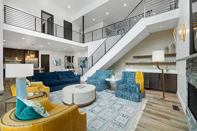 3132 N Atlas Rd, Coeur Dalene, ID 83814 - living room with stairway, a stone fireplace, light wood finished floors, a high ceiling, and a notable chandelier