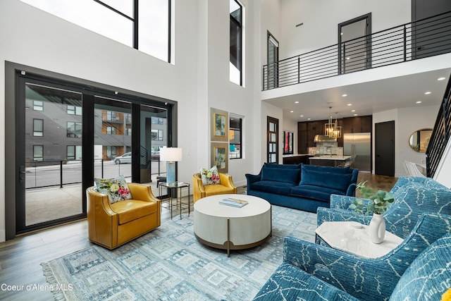 3132 N Atlas Rd, Coeur Dalene, ID 83814 - living room featuring light wood-style flooring, a high ceiling, a notable chandelier, and a healthy amount of sunlight