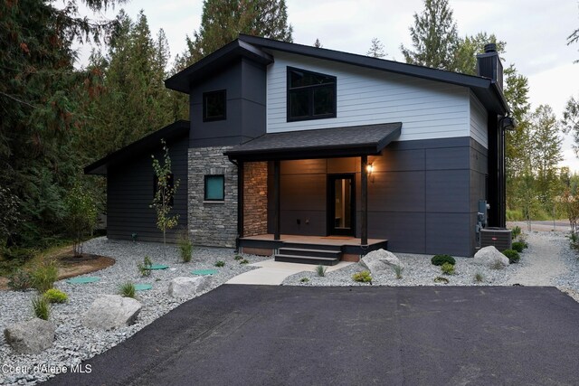70 Wedge Ct, Priest Lake, ID 83856 - contemporary house with stone siding, a chimney, and central AC unit