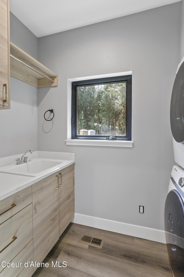 70 Wedge Ct, Priest Lake, ID 83856 - laundry area with a sink, dark wood finished floors, baseboards, stacked washer and clothes dryer, and visible vents