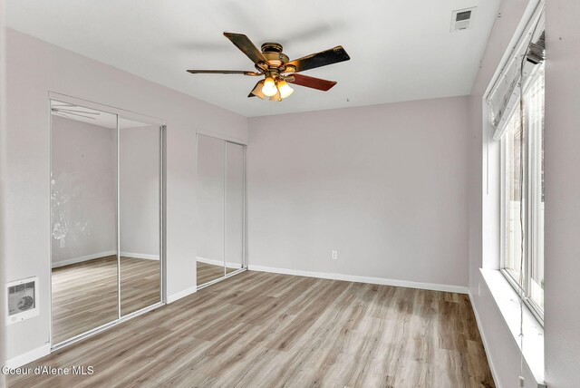 1002 E St Elias Ct, Post Falls, ID 83854 - unfurnished bedroom featuring wood finished floors, two closets, ceiling fan, baseboards, and visible vents