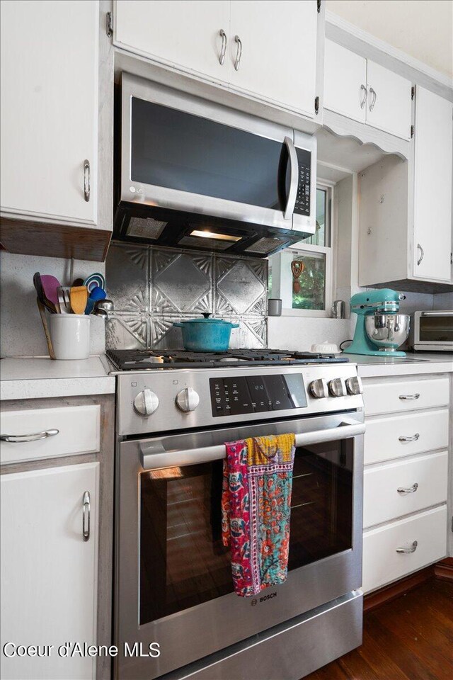 917 E Young Ave, Coeur Dalene, ID 83814 - kitchen with appliances with stainless steel finishes, light countertops, backsplash, white cabinetry, and dark wood-style floors