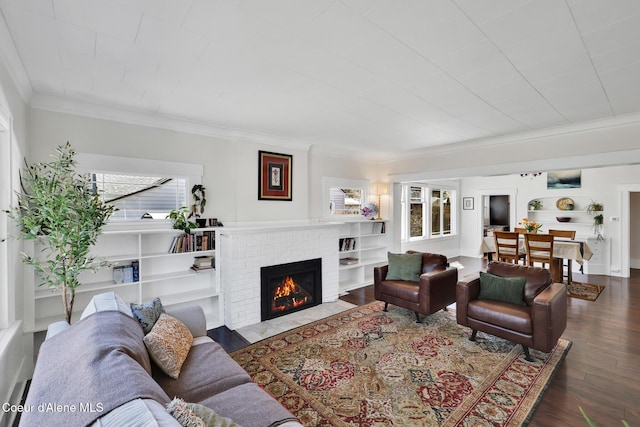 living room with crown molding, a brick fireplace, and wood finished floors