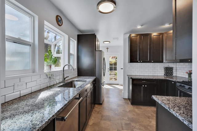 kitchen with appliances with stainless steel finishes, tasteful backsplash, a sink, and a healthy amount of sunlight