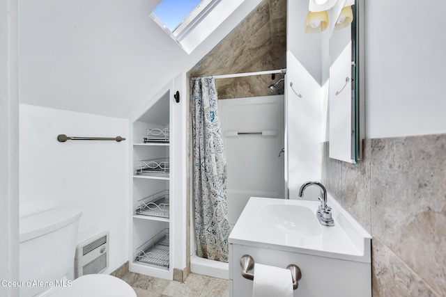 bathroom featuring a shower stall, vanity, toilet, and a skylight
