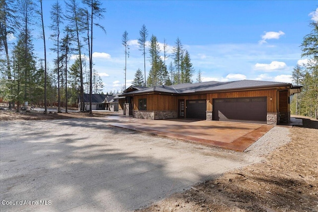 view of front of property with stone siding, an attached garage, and driveway