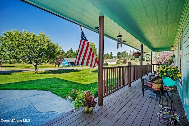 wooden terrace featuring a lawn and covered porch