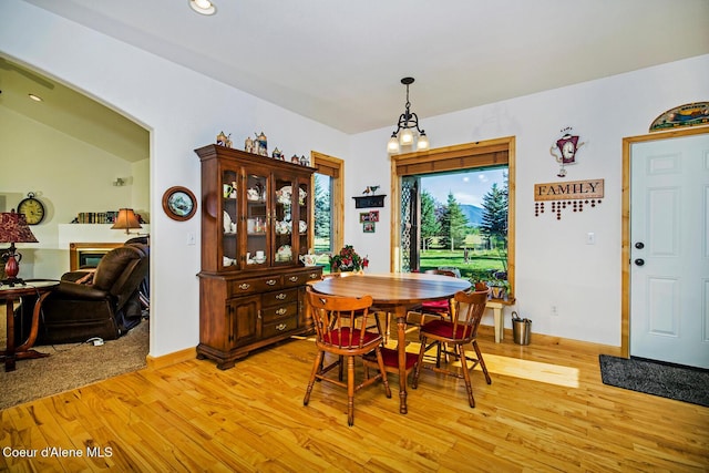 dining area featuring recessed lighting, light wood-style floors, a glass covered fireplace, and baseboards