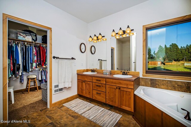 full bath with a tub to relax in, double vanity, a walk in closet, and a sink
