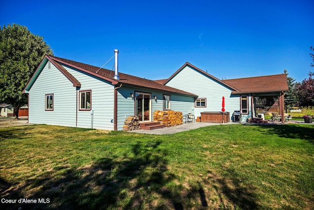 rear view of property featuring a hot tub, a yard, a patio, and a shingled roof