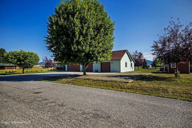 view of front facade featuring driveway, a front yard, an outbuilding, and a garage